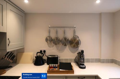 una cocina con ollas y sartenes colgadas en la pared en Boutique cottage in the heart of Winchcombe, en Winchcombe