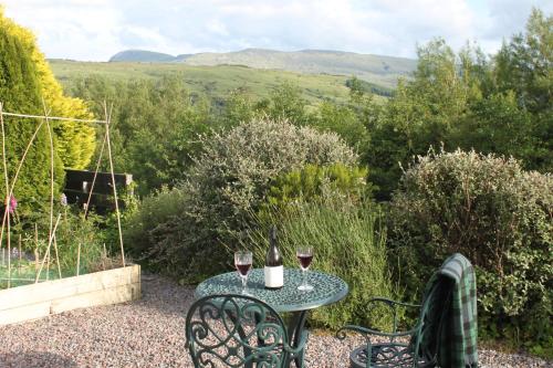 a table with two glasses of wine on a patio at Heatherbank Guest House in Strontian