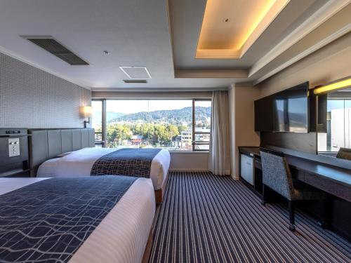 京都市にあるアパホテル〈京都祇園〉EXCELLENTのベッド2台、デスク、窓が備わるホテルルームです。