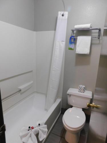 a white bathroom with a toilet and a bath tub at Days Inn & Suites by Wyndham Downtown Gatlinburg Parkway in Gatlinburg