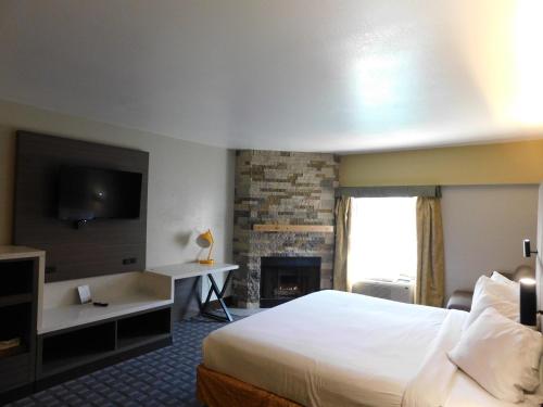 um quarto de hotel com uma cama e uma lareira em Days Inn & Suites by Wyndham Downtown Gatlinburg Parkway em Gatlinburg