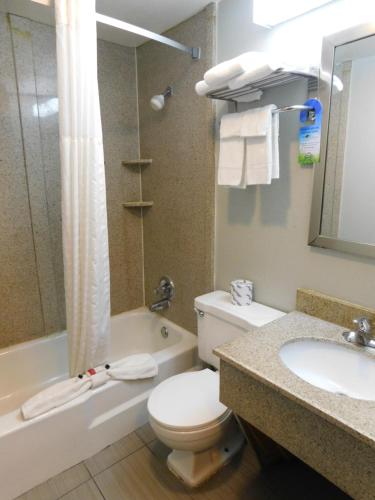 a bathroom with a toilet and a tub and a sink at Days Inn & Suites by Wyndham Downtown Gatlinburg Parkway in Gatlinburg