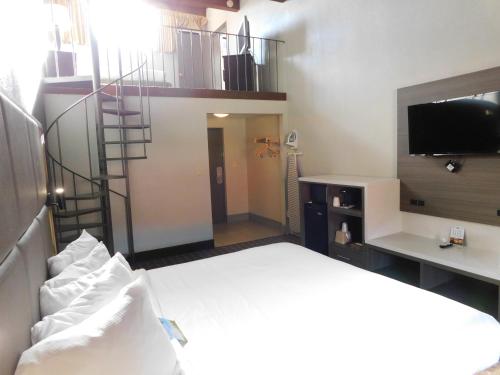 a bedroom with a bed and a tv and a staircase at Days Inn & Suites by Wyndham Downtown Gatlinburg Parkway in Gatlinburg