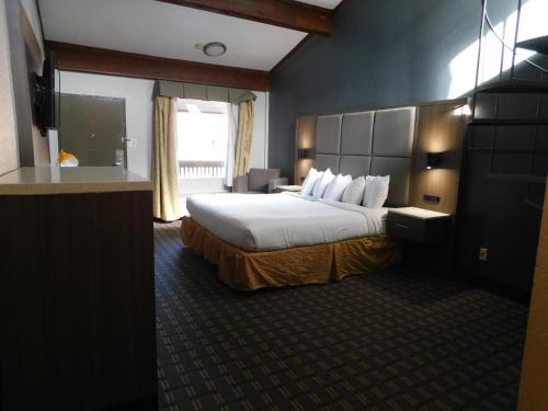 a hotel room with a bed and a television at Days Inn & Suites by Wyndham Downtown Gatlinburg Parkway in Gatlinburg