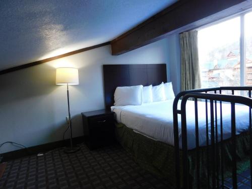a hotel room with a bed and a window at Days Inn & Suites by Wyndham Downtown Gatlinburg Parkway in Gatlinburg