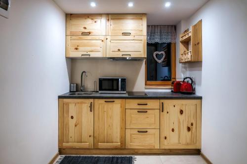a kitchen with wooden cabinets and a microwave at Willa w Ubocy - "Jacuzzi i Sauna w ofercie dodatkowo płatnej" in Murzasichle