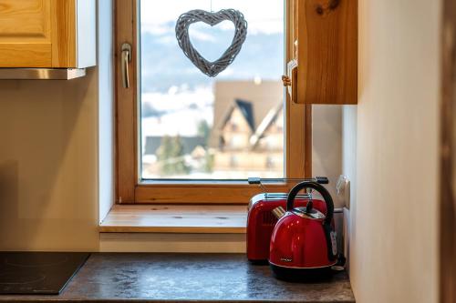 a kitchen with a heart window and a red appliance at Willa w Ubocy - "Jacuzzi i Sauna w ofercie dodatkowo płatnej" in Murzasichle