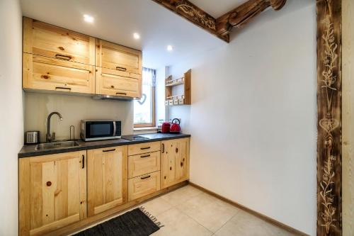 a kitchen with wooden cabinets and a microwave at Willa w Ubocy - "Jacuzzi i Sauna w ofercie dodatkowo płatnej" in Murzasichle