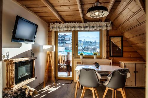 a living room with a table and chairs and a television at Willa w Ubocy - "Jacuzzi i Sauna w ofercie dodatkowo płatnej" in Murzasichle