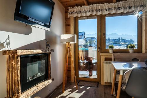 a living room with a fireplace and a flat screen tv at Willa w Ubocy - "Jacuzzi i Sauna w ofercie dodatkowo płatnej" in Murzasichle
