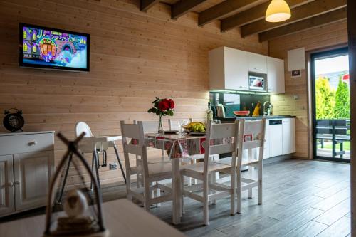 eine Küche mit einem Tisch und Stühlen sowie einem TV in der Unterkunft Amelia Domki in Sianożęty