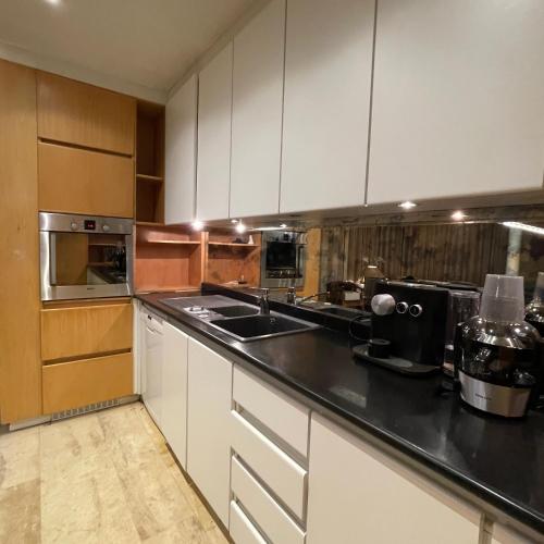 a kitchen with white cabinets and stainless steel appliances at Ellé'Belle Oudsbergen 1-, 2- or 3-Bedrooms in Oudsbergen 