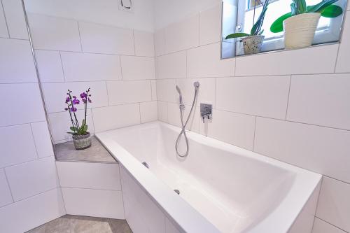 a white bath tub in a white tiled bathroom at Bergblick Acht Mondsee in Innerschwand am Mondsee