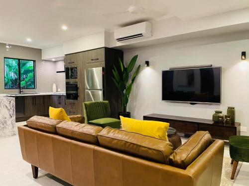 a living room with a brown couch and a flat screen tv at Lahania Lux Beach Villa in Clifton Beach