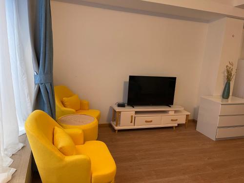 a living room with two yellow chairs and a television at Gîtes Sax 2 in Dinant