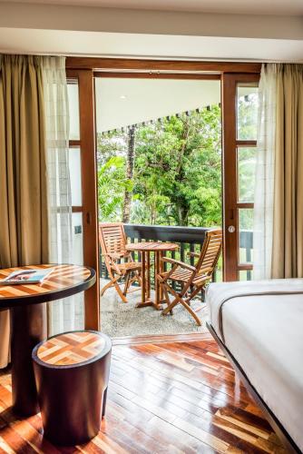 a room with a balcony with a table and chairs at The Warwick Fiji in Korolevu
