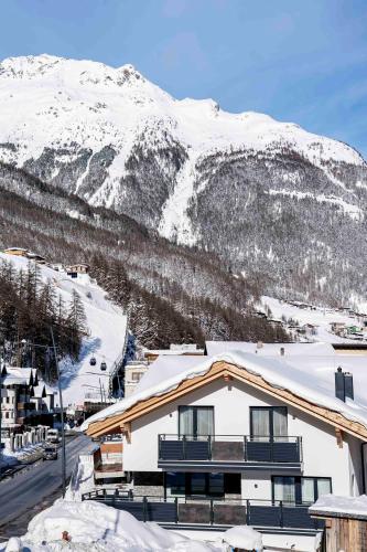 a building with snow covered mountains in the background at Landhaus Martinus in Sölden