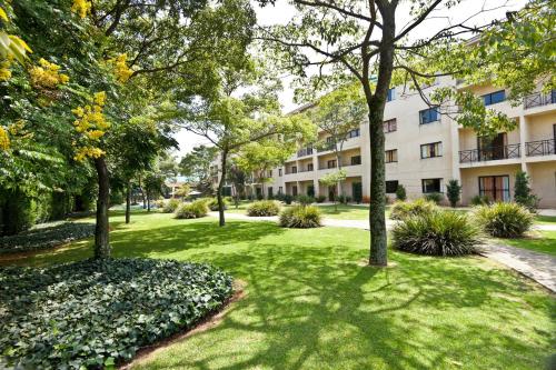 a park with trees and grass in front of a building at Hotel Panamby Guarulhos in Guarulhos