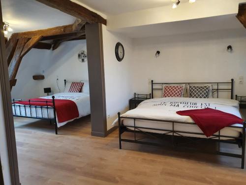 a bedroom with two beds and a clock on the wall at au Petit Paradis in Sainte-Gauburge-Sainte-Colombe