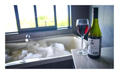 a bottle of wine sitting next to a tub with a glass at Luxury Seaview Apartments in Greymouth