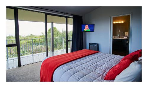 a bedroom with a bed and a balcony with a television at Luxury Seaview Apartments in Greymouth