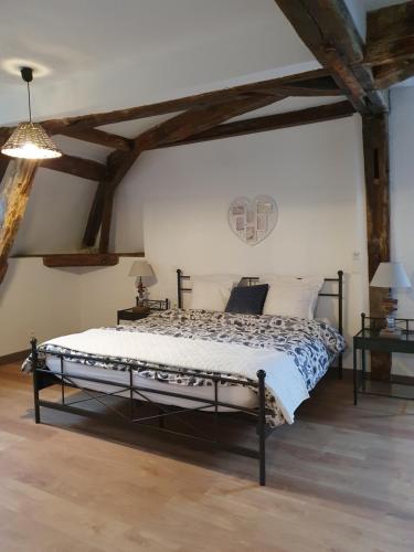 a bedroom with a bed in a room with wooden ceilings at au Petit Paradis in Sainte-Gauburge-Sainte-Colombe