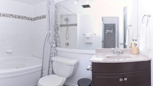 a white bathroom with a toilet and a sink at Comfortable Townhouse in Whistler Village w Hot Tub in Whistler