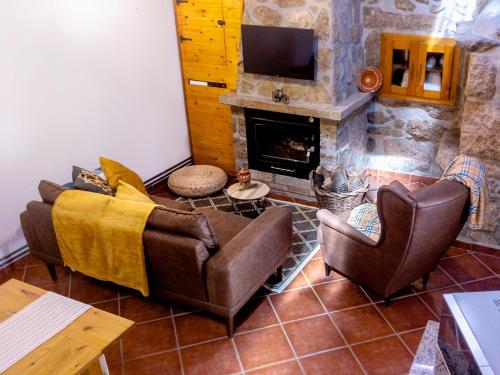 a living room with couches and a stone fireplace at Refúgio do Óscar in Gavieira