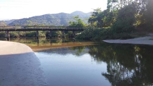 een brug over een rivier met een reflectie in het water bij CONDOMÍNIO ILHAS DO JUQUEHY in Sao Paulo