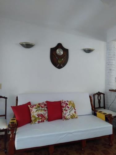 a white couch with a clock on a white wall at CONDOMÍNIO ILHAS DO JUQUEHY in Juquei