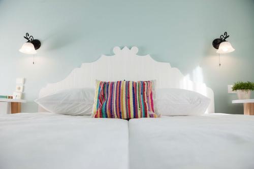 a white bed with a striped pillow on it at 7 Brothers Hotel in Poros