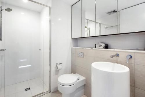a white bathroom with a toilet and a shower at Oracle Resort Broadbeach - gclr in Gold Coast