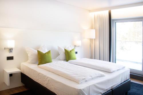 a bedroom with a large white bed with green pillows at KF Hotel by WMM Hotels in Kaufbeuren