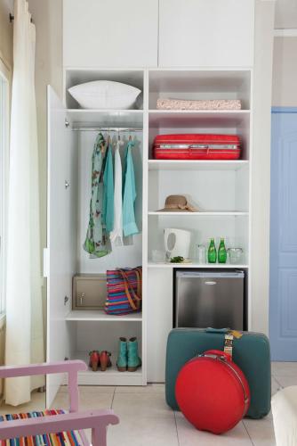 a white closet with a red suitcase in a room at 7 Brothers Hotel in Poros