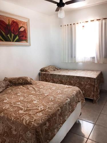 a bedroom with two beds and a painting on the wall at Recanto Casa de Pedrinha - Aptos para temporada e finais de semana in Caraguatatuba