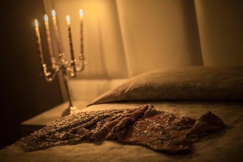 a bed with two candles on a table in a room at Artemisia Palace Hotel in Palermo