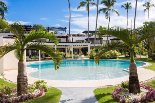 a swimming pool with palm trees in front of a building at Oasis Apartment C4 inside ALIGIO Residence Hotel in Las Terrenas