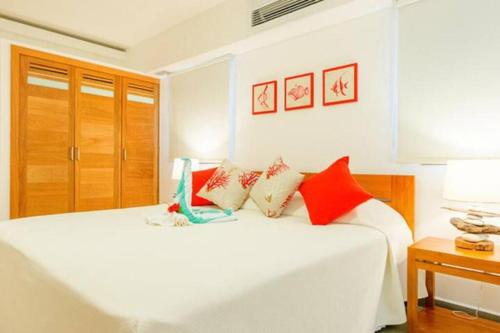 a bedroom with a white bed with red pillows at Oasis Apartment C4 inside ALIGIO Residence Hotel in Las Terrenas