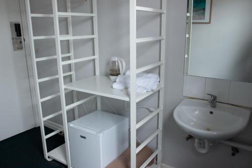 uma casa de banho com uma prateleira de livros brancos ao lado de um lavatório em Grand Hotel Rockdale em Sydney