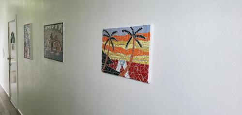 a group of paintings on a white wall at Palmeras Del Mar in Isabela