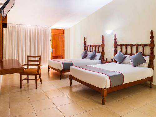 韋拉克魯斯的住宿－Collection O Hotel Mocambo, Boca del Río，一间卧室配有两张床、一张桌子和一张书桌