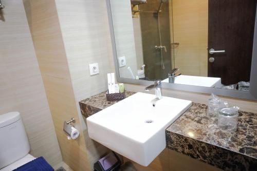 a bathroom with a sink and a toilet and a mirror at Harmoni Hotel Garut in Garut