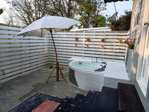 a bath tub with an umbrella next to a building at Terrua Main Ten Villa Garden in Suan Phung