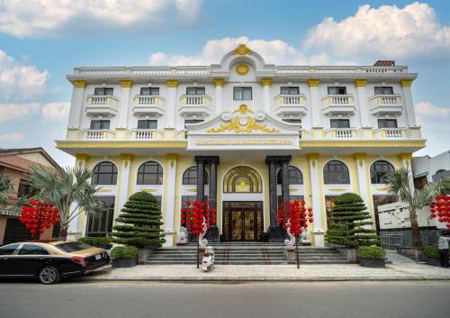 會安的住宿－Le Pavillon Hoi An Gallery Hotel & Spa，一座白色的大建筑,前面有红花