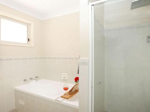 a white bathroom with a tub and a glass shower at That Pink House in Bowral