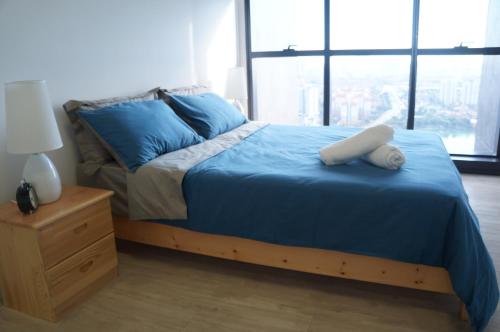 sypialnia z łóżkiem z niebieską pościelą i szafką nocną w obiekcie M City Lake View 1+1 Room w Kuala Lumpur