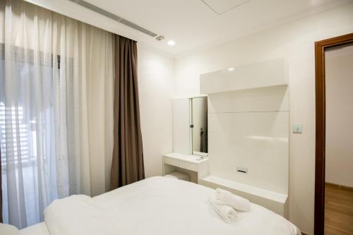 Una habitación blanca con una cama y un espejo. en BOM HOMES- VINHOMES TIMES CITY & PARK hilll, en Hanói