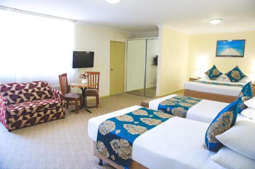 a hotel room with two beds and a chair at Ryde Inn in Sydney