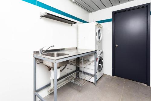 a kitchen with a sink and a washing machine at Airlie Sun & Sand Accommodation #2 in Airlie Beach