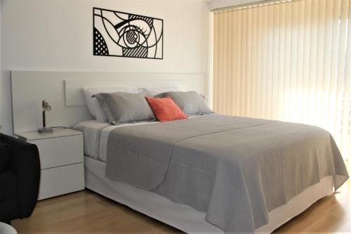 um quarto branco com uma cama grande e uma almofada laranja em Petite Maison II em Buenos Aires
